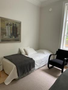 a white bedroom with a bed and a chair at Old Turku Family Apartment in Turku