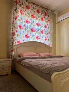 a bedroom with a bed with a curtain with flowers at Eurasia hotel in Almaty