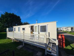 a mobile home with a porch and a deck at Destiny Caravan Hire in Skegness