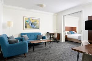 una camera d'albergo con sedie blu e un letto di Quest West End a Perth