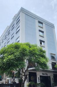a tall white building with a tree in front of it at Hotel Star City in Chennai