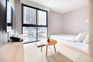 a bedroom with a bed and a table and a window at LiveZen Bangkok Sukhumvit in Khlong Toei