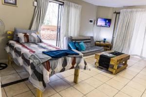 a bedroom with a bed and a couch and a tv at Stamvrug 9 B in Nelspruit