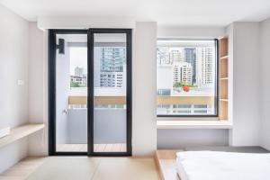 a bedroom with a glass door leading to a window at LiveZen Bangkok Sukhumvit in Khlong Toei