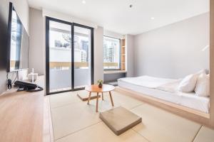 a bedroom with a bed and a table and windows at LiveZen Bangkok Sukhumvit in Khlong Toei