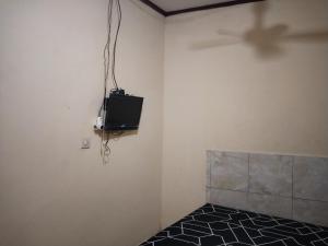 een kamer met een tv aan de muur bij OYO Life 93156 Rumah Kosan in Tanjung