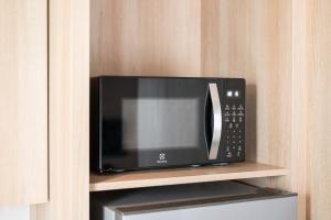 a black microwave sitting on a shelf in a kitchen at LiveZen Bangkok Sukhumvit in Khlong Toei