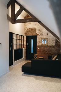 uma sala de estar com um sofá preto e uma parede de tijolos em Gezellige loft met twee slaapkamers em Ieper