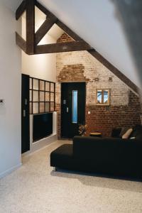 a living room with a black couch and a brick wall at Gezellige loft met twee slaapkamers in Ypres +16 photos