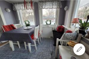 a dining room with a table and chairs and windows at En liten trevlig villa nära stranden och travbanan. in Eskilstuna