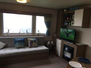 a living room with a couch and a television at Devon Cliffs Exmouth Sandy Bay 3 bedrooms in Exmouth