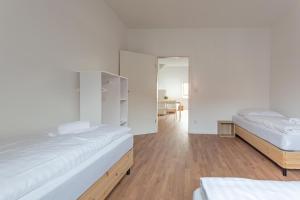 Ce lit se trouve dans un dortoir doté de murs blancs et de parquet. dans l'établissement T&K Apartments - DUISBURG - Frisch renovierte 4 Zimmer Maisonetten mit Privatparkplätzen, à Duisbourg