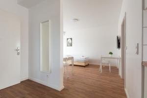 Il comprend un salon doté de murs blancs et de parquet. dans l'établissement T&K Apartments - DUISBURG - Frisch renovierte 4 Zimmer Maisonetten mit Privatparkplätzen, à Duisbourg