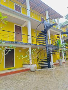 un bâtiment jaune avec un escalier en colimaçon. dans l'établissement Paradise Le Tamarin, à Auroville