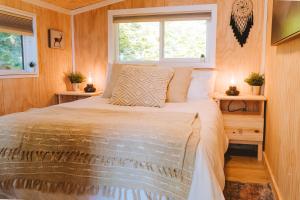 Cama en habitación pequeña con ventana en Kootenay Lakeview Retreats - Forest Cabin, en Nakusp