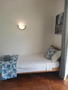 Cama pequeña en habitación con pared blanca en Artists house en Rivière Noire