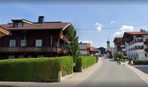 a street in a town with houses and a person riding a bike at Appartement Wurzrainer in Westendorf