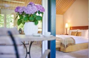 ein Schlafzimmer mit einem Bett und einer Vase mit lila Blumen in der Unterkunft Hotel Hohenhaus in Herleshausen