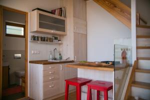 a small kitchen with two red stools and a sink at Ég & Föld Borvendégház in Szekszárd