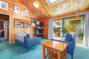 ein Wohnzimmer mit 2 blauen Stühlen und einem Tisch in der Unterkunft Five Mile Yay - Five Mile Bay Holiday Home in Taupo