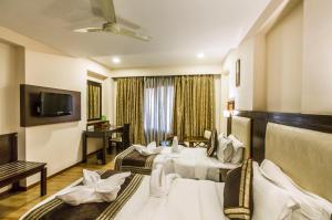 um quarto de hotel com duas camas e uma televisão em Golden Manor By Brand My Hotel em Jaipur