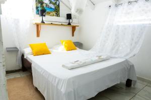 - une chambre avec 2 lits avec des oreillers jaunes et une fenêtre dans l'établissement La villa du soleil 971, à Anse-Bertrand