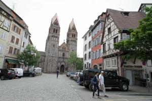 Un groupe de personnes marchant dans une rue avec une église dans l'établissement Gite Le Caveau Sélestat - 30min EuropaPark, à Sélestat