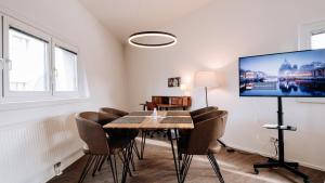 een eetkamer met een tafel en stoelen en een flatscreen-tv bij URBAN ISLAND I Riverside Apartments in Wenen