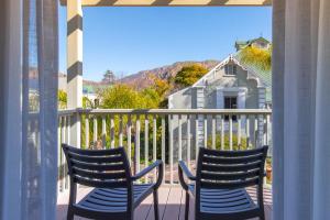 twee stoelen op een balkon met een huis bij Montagu Country Hotel in Montagu