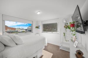 een witte slaapkamer met een bed en een raam bij A Larger Slice of Fremantle 3bed apt. Wifi-Netflix in Fremantle