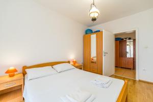 Schlafzimmer mit einem weißen Bett und Holzmöbeln in der Unterkunft Apartments Zora in Lun