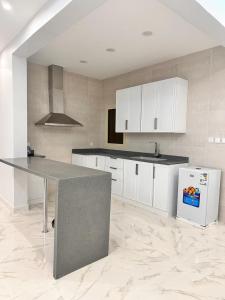 a kitchen with white cabinets and a table and a refrigerator at سحاب in Yanbu
