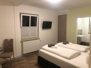 1 dormitorio con 2 camas, ventana y silla en Pension Krug zum Schlaubetal en Mixdorf
