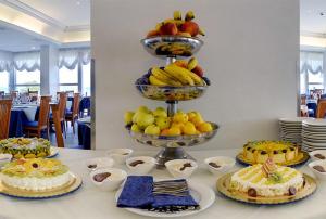 a table topped with cakes and fruit on plates at Hotel Margareth in Riccione