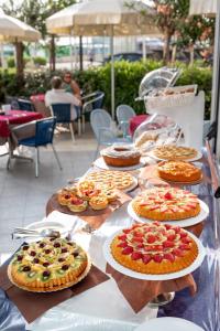 une table recouverte de tartes et de gâteaux sur des assiettes dans l'établissement Hotel Margareth, à Riccione