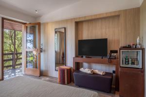a bedroom with a tv and a couch in a room at Vallegrande Nature Resort by Geocharme in Cefalù