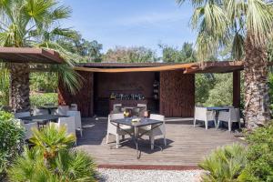 a patio with tables and chairs and palm trees at Vallegrande Nature Resort by Geocharme in Cefalù