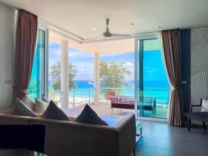 een woonkamer met een bank en uitzicht op de oceaan bij Paradox Resort Phuket - SHA Plus in Karon Beach