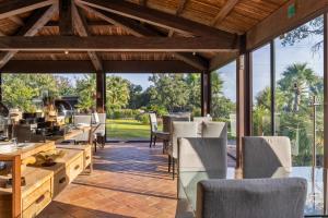 an open patio with chairs and tables and windows at Vallegrande Nature Resort by Geocharme in Cefalù