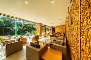 a lobby with chairs and tables and a wall of windows at Hana Beppu in Beppu