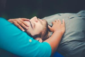 Un homme qui se couche sur un lit à côté d'une femme dans l'établissement PWL Healing Retreat Accommodation, à Rotorua