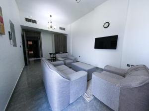 a living room with couches and a flat screen tv at Warsan Star Residence - Home Stay in Dubai