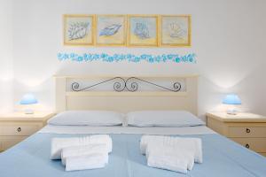 a bedroom with a blue bed with two white towels at Villetta Bougainvillea in San Teodoro