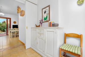 a living room with a white cabinet and a chair at Villetta Bougainvillea in San Teodoro