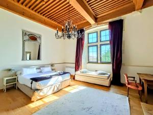 1 dormitorio con cama, mesa y lámpara de araña en Les Chambres De La Renaissance en Sainte-Julie