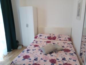 a small bedroom with a bed with a floral bedspread at Ana Rooms in Krk