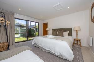 a bedroom with two beds and a large window at Wanaka Deluxe Studio in Wanaka