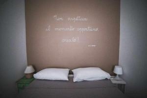 a bed with two white pillows and words on the wall at LE DIMORE DEGLI ARTISTI Vico Mercatello in Venosa