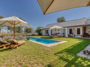 a backyard with a pool and chairs and an umbrella at Explorer Guesthouse in Somerset West