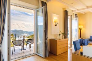 um quarto com uma porta que abre para uma varanda em Kurhaus Cademario Hotel & DOT Spa - Ticino Hotels Group em Cademario